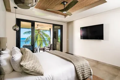 a bedroom with a white bed and a flat screen tv at Beachfront Luxury Villa, 2 Pools & Daily Breakfast in Playa Flamingo