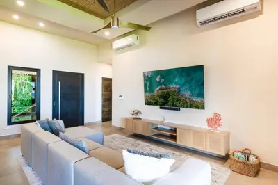 a living room with a couch and a tv at Beachfront Luxury Villa, 2 Pools & Daily Breakfast in Playa Flamingo