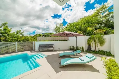 a swimming pool with two blue chairs and an umbrella at Ocean-View Villa, Pool & Concierge in Ocotal