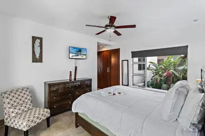 a bedroom with a bed with a ceiling fan and a chair at Garden View, Patio, Steps to Sand with Pool in Potrero