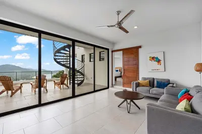 a living room with a couch and a spiral staircase at Infinity Pool Haven, Ocean Views & Concierge in Potrero