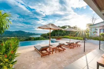 a patio with chairs and umbrellas and a pool at Infinity Pool Haven, Ocean Views & Concierge in Potrero