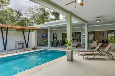 a swimming pool with two chairs and a house at Fun Packed Family Vacation in Playa Flamingo