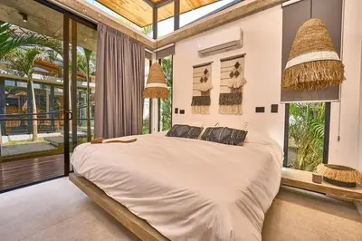 a bedroom with a large bed in a room with windows at Buho Vibe Earthy Elegance in Tamarindo