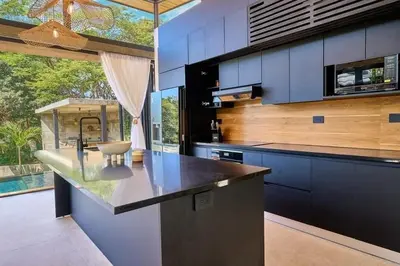 a kitchen with blue cabinets and a large window at Buho Vibe Earthy Elegance in Tamarindo