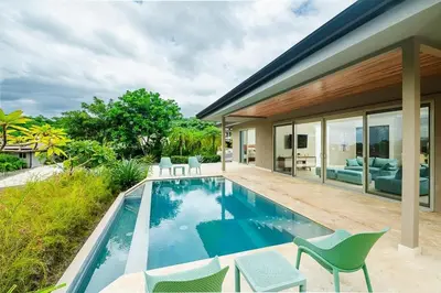 a swimming pool with chairs and a house at Exclusive Villa in Mar Vista Community in Playa Flamingo