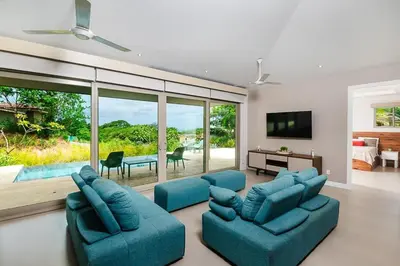 a living room with two blue couches and a tv at Exclusive Villa in Mar Vista Community in Playa Flamingo
