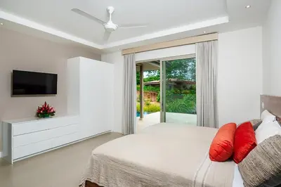 a white bedroom with a bed and a tv at Exclusive Villa in Mar Vista Community in Playa Flamingo