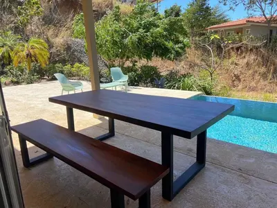 a wooden table and a bench next to a pool at Exclusive Villa in Mar Vista Community in Playa Flamingo