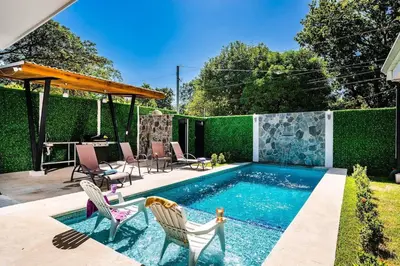 a swimming pool in a yard with chairs at Private Pool Ping-Pong Table Walk to Beach Villa in Playa Flamingo