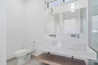 a white bathroom with two sinks and a toilet at Modern Villa 5 BD 4 BA Large Pool in Playa Avellana