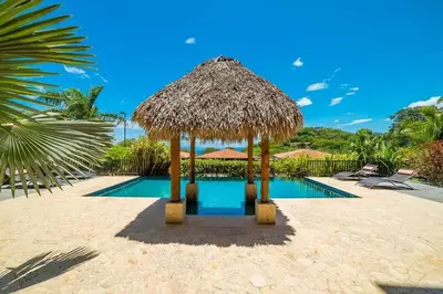 a resort with a swimming pool and a straw hut at Captivating Ocean Views Condo with Pool in Ocotal