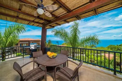 a balcony with a table and chairs and the ocean at Captivating Ocean Views Condo with Pool in Ocotal
