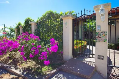 a gate with pink flowers in front of a house at Luxury Villa, Infinity Pool & Ocean Views in Potrero
