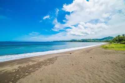 a sandy beach with people in the water at Luxury Villa, Infinity Pool & Ocean Views in Potrero