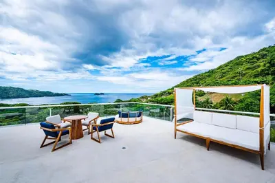 a balcony with a table and chairs and the ocean at Spacious Villa Retreat in Private Resort in Playa Hermosa