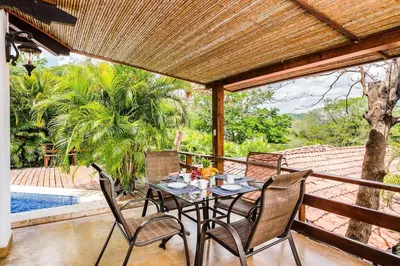 a table and chairs on a patio with a pool at Spacious Villa Retreat in Private Resort in Playa Hermosa