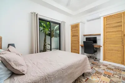 a bedroom with a bed and a desk and a window at Pool Paradise Steps from Beach & Restaurants in Playa Flamingo