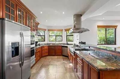 a kitchen with wooden cabinets and a stainless steel refrigerator at Spectacular Ocean Views Infinity Pool in Potrero