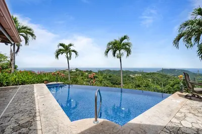 a pool with palm trees and a view of the ocean at Spacious Villa with Infinity Pool & Ocean View in Potrero