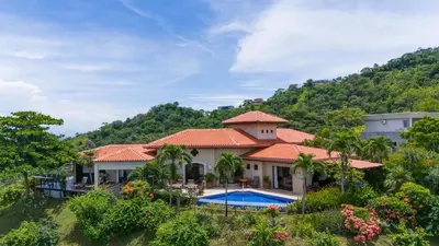 a house with a swimming pool in front of a mountain at Spacious Villa with Infinity Pool & Ocean View in Potrero