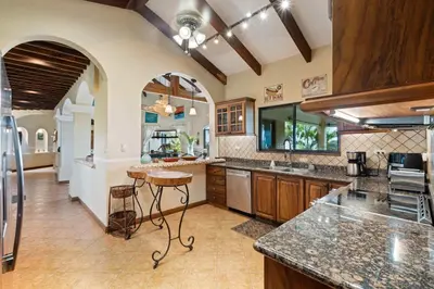 a large kitchen with granite counter tops and wooden cabinets at Spacious Villa with Infinity Pool & Ocean View in Potrero