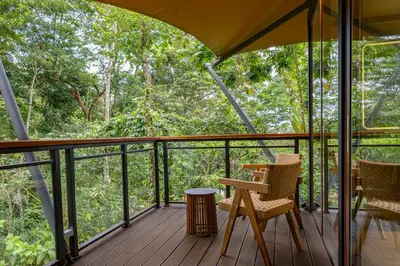 a screened in porch with two chairs and a table at Tifakara by the Waterfall in Fortuna