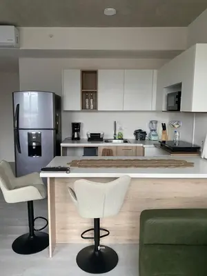 a kitchen with a counter and two chairs and a refrigerator at Hermoso y Acogedor Studio Sabana, San Jose in San José