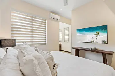 a bedroom with a bed with white sheets and a window at Stylish Condo in the Heart of Las Catalinas with Vibrant Design & Exclusive Beach Club Access in Playa Danta