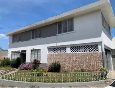 a white house with a brick fence in front of it at Linda y céntrica habitación in Alajuela City