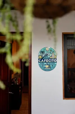 a sign on the side of a white wall at The Cafecito Surfhouse - Santa Teresa in Santa Teresa Beach