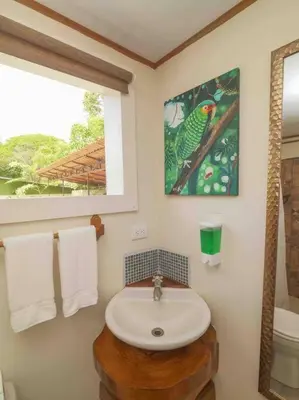 a bathroom with a sink and a bird painting on the wall at Private Villa with Pool near Manuel Antonio beach in Naranjito