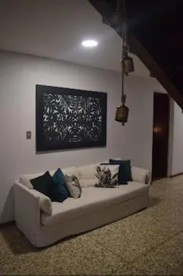 a living room with a white couch with pillows at Acogedora y amplia habitación en La Tropicana in Alajuela City