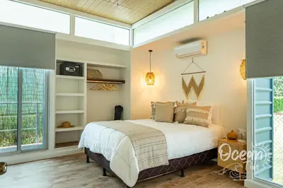 a bedroom with a bed and a large window at Oceantide Playa Hermosa in Playa Hermosa