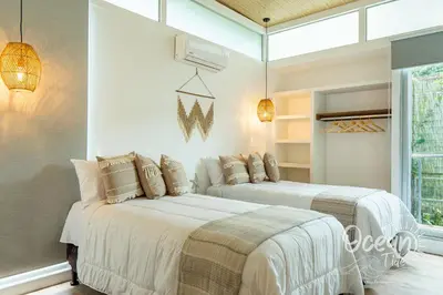 two beds in a bedroom with white walls at Oceantide Playa Hermosa in Playa Hermosa
