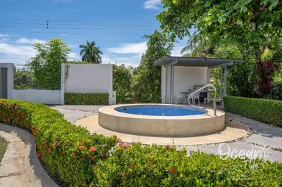 a swimming pool in a garden with an umbrella at Oceantide Playa Hermosa in Playa Hermosa