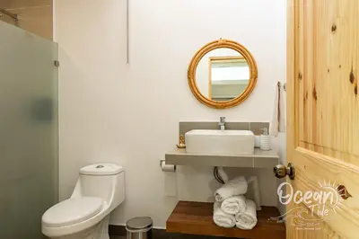 a bathroom with a toilet and a sink and a mirror at Oceantide Playa Hermosa in Playa Hermosa