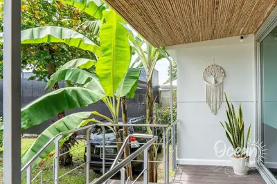 a porch with a palm tree and a chair at Oceantide Playa Hermosa in Playa Hermosa