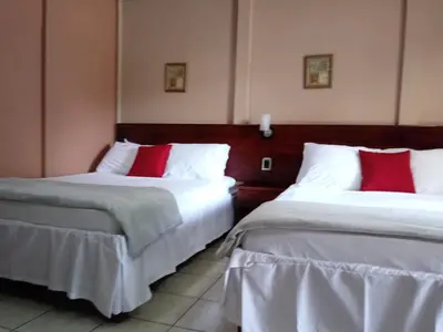 two beds in a hotel room with red pillows at Hotel Boutique Malibu Los Sueños in Tigre