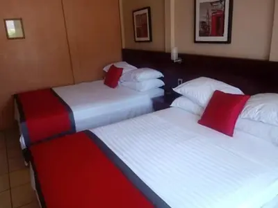 three beds in a hotel room with red pillows at Hotel Boutique Malibu Los Sueños in Tigre