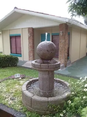 a stone fountain in front of a house at Hotel Boutique Malibu Los Sueños in Tigre