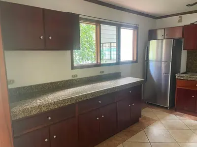 a kitchen with brown cabinets and a stainless steel refrigerator at Comparte con la Naturaleza in Escazu