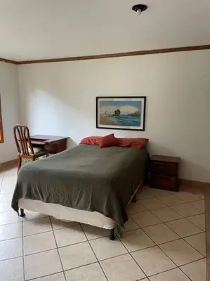 a bedroom with a bed and a table with a chair at Comparte con la Naturaleza in Escazu