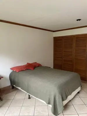 a bedroom with a large bed and wooden cabinets at Comparte con la Naturaleza in Escazu