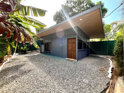 a house with a blue facade with a gravel driveway at `Luci's Home' in Uvita