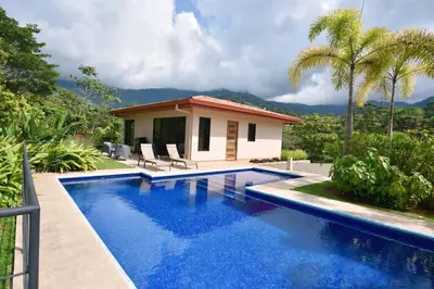 a villa with a swimming pool in front of a house at Villa Romancing The Stone in Ojochal