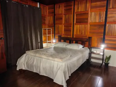 a bedroom with a bed with wooden walls at Cabaña Colibri #2 in Quesada