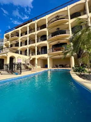 a hotel with a swimming pool in front of a building at Majestic Oceanview Condo with King Beds in Coco