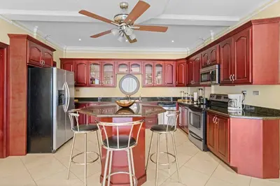 a kitchen with red cabinets and a ceiling fan at Majestic Oceanview Condo with King Beds in Coco