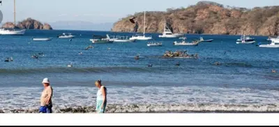 two people walking on the beach with boats in the water at Renovated apartment in Las Palmas in Coco